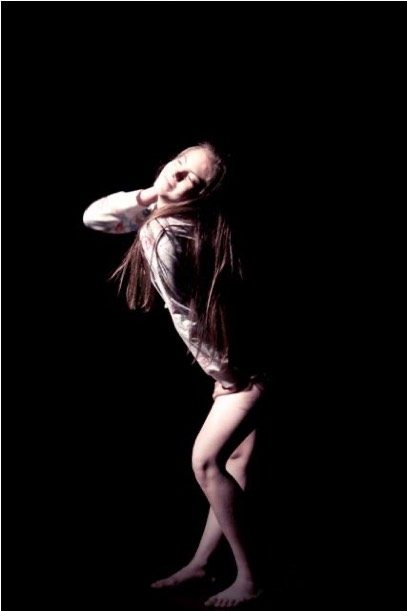 A dancer bending backwards under a single light in the piece Frívolo.