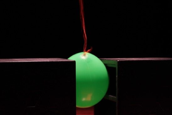 A green balloon lit from below, vibrating on a resonating structure during the INFRA sound performance.